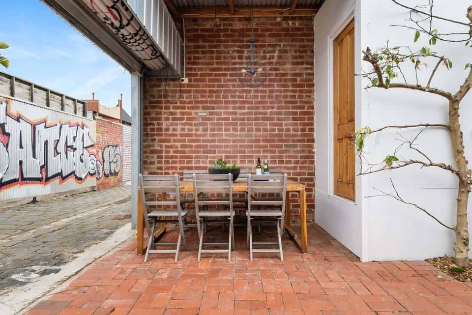 OUTDOOR DINING: The rear courtyard with outdoor table setting opens to the rear lane for car parking access.