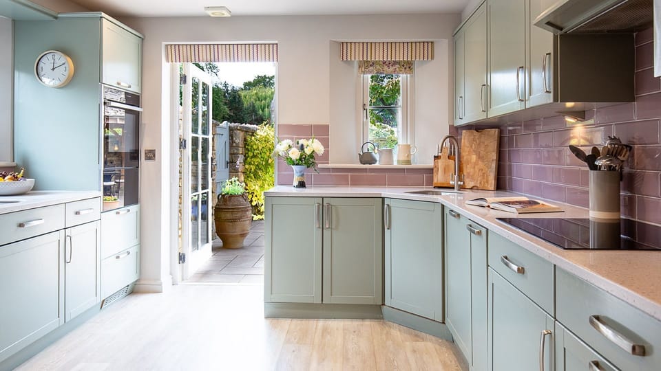 The colourful cottage kitchen has everything you need with an extra pop of personality with pale blue units and delicate purple tiling.