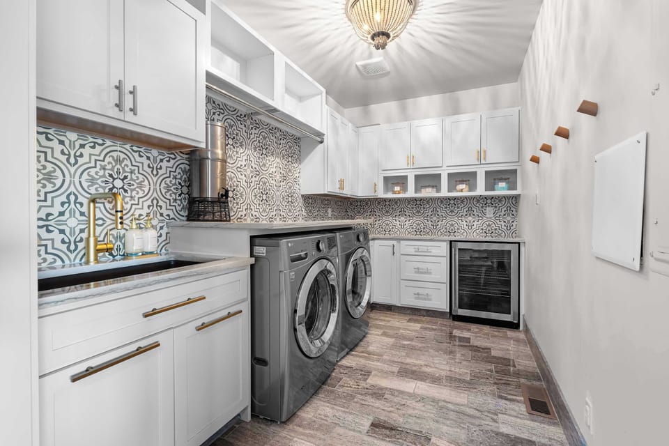 Even chores feel elevated here ... a designer laundry space featuring a patterned tile backsplash, gold accents, and extra touches like a wine fridge and water filter. Function meets luxury at every turn.