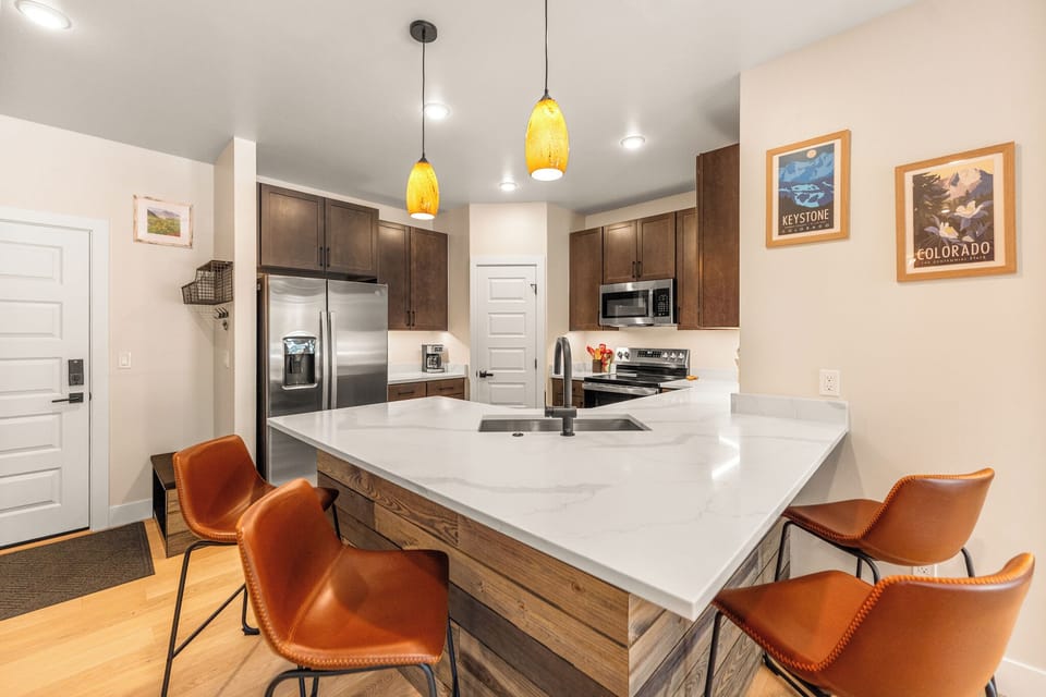 Cook together in your modern kitchen featuring warm wood cabinets, bright pendant lights, and stylish seating at the oversized island.