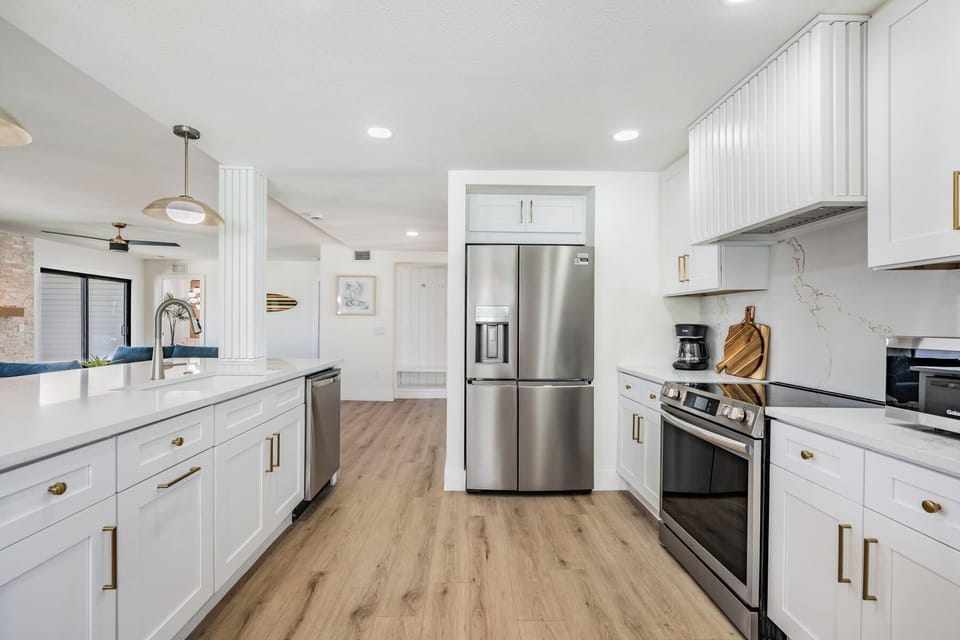Sleek and airy kitchen featuring stainless steel appliances, white cabinetry, and quartz countertops. The open design and modern finishes make it perfect for cooking, entertaining, or simply enjoying coffee with a view of the bright living area.