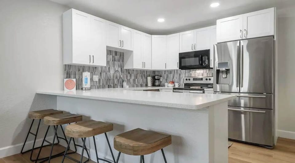 Sleek modern kitchen featuring stainless steel appliances, quartz countertops, and stylish backsplash. Enjoy casual dining at the breakfast bar with rustic stools—perfect for morning coffee or evening meals in comfort and style.