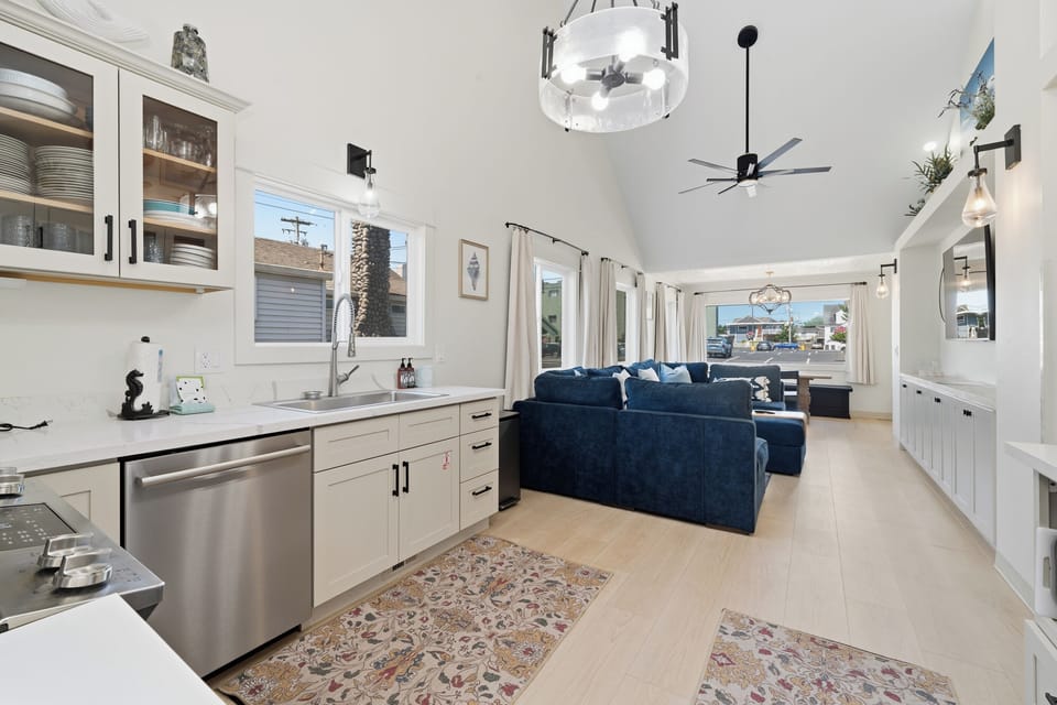 Step into your bright, open-concept retreat where sleek white cabinetry meets plush velvet seating. Soaring vaulted ceilings and gleaming floors create an airy, coastal-chic vibe—perfect for unwinding after a day of adventure.