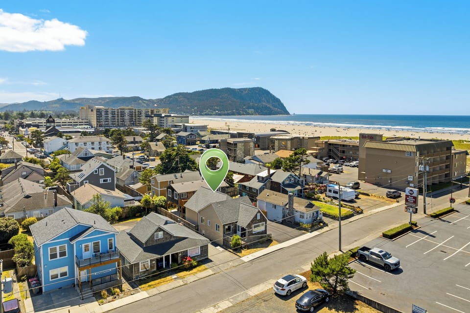 Aerial view of a coastal neighborhood with residential properties near the beach and ocean. The property is located in a charming seaside town with mountain and sea views.