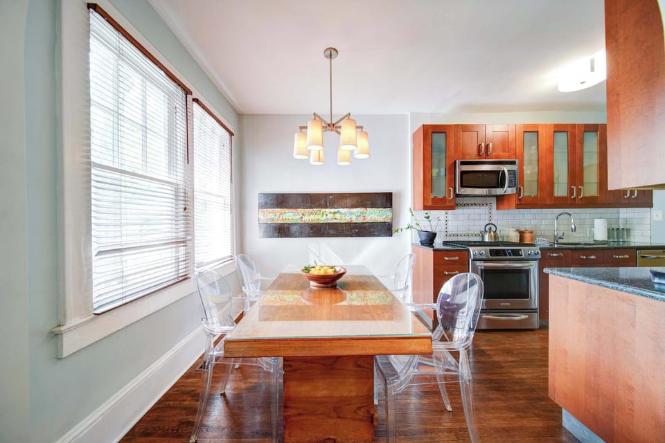Open dining area in Charlotte featuring a modern table, pendant lighting, and seamless flow into the fully equipped kitchen. Bright, functional space ideal for meals, remote work, or gathering during your stay in the city.