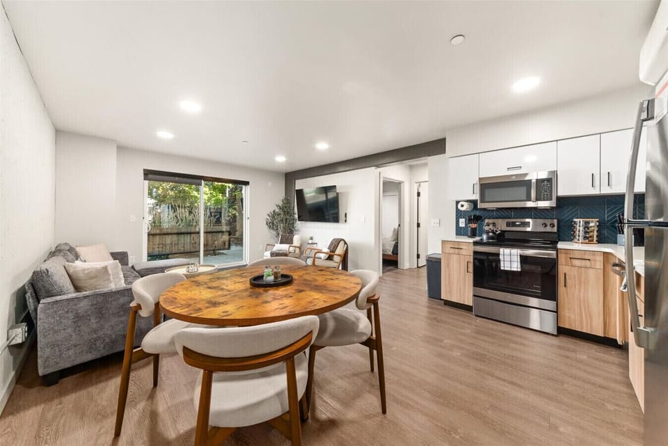 - Gather for meals in a modern open layout with a wood dining table and cushioned chairs   - Seamless flow connects the dining area, kitchen, and cozy living space   - Perfect for group dining, family games, or a peaceful morning coffee moment