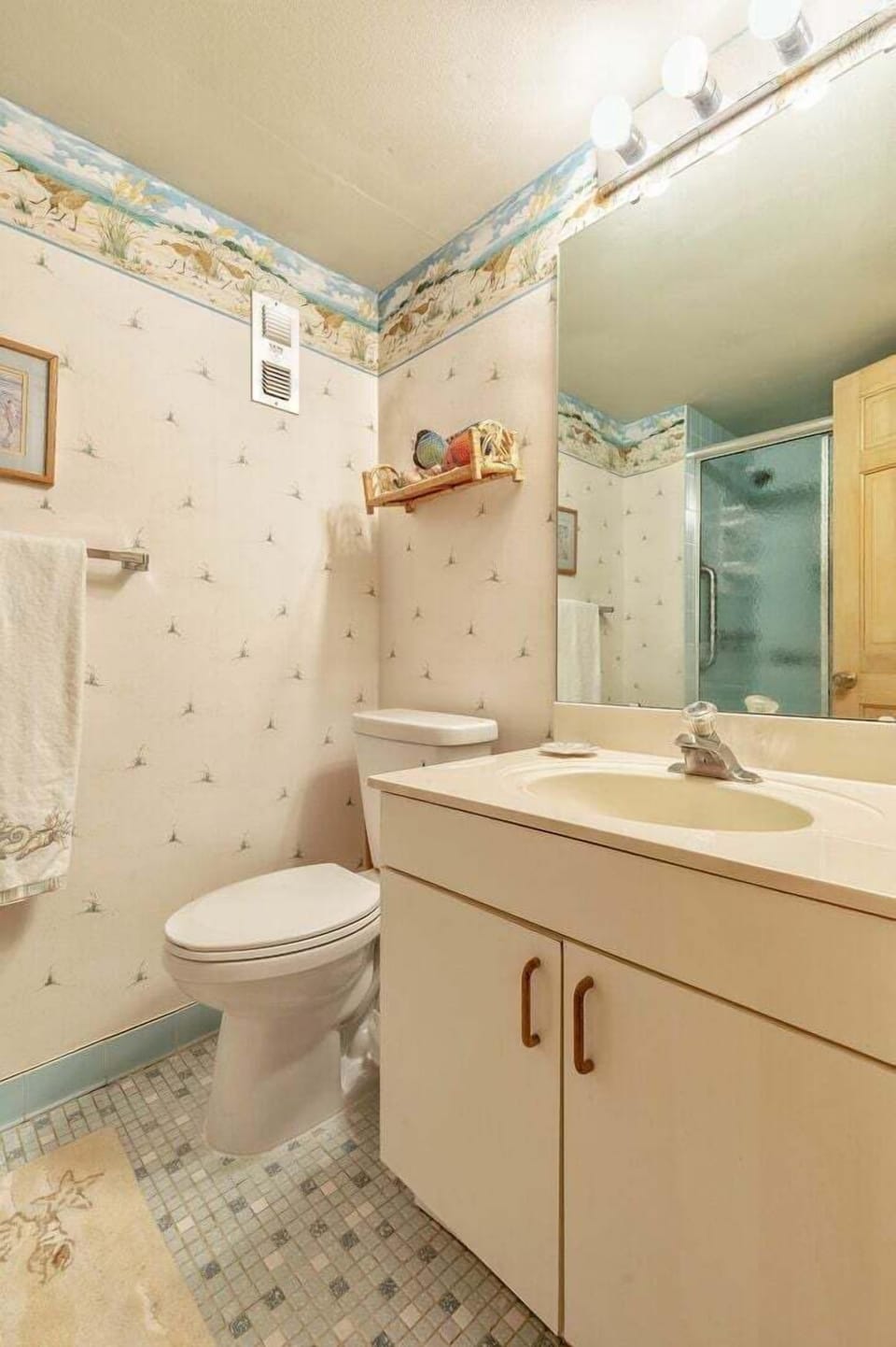 Enjoy this cozy beach-themed bathroom featuring bright coastal décor, a spacious vanity, and a refreshing shower—perfect for freshening up after a day of fun in the sun during your beach stay.