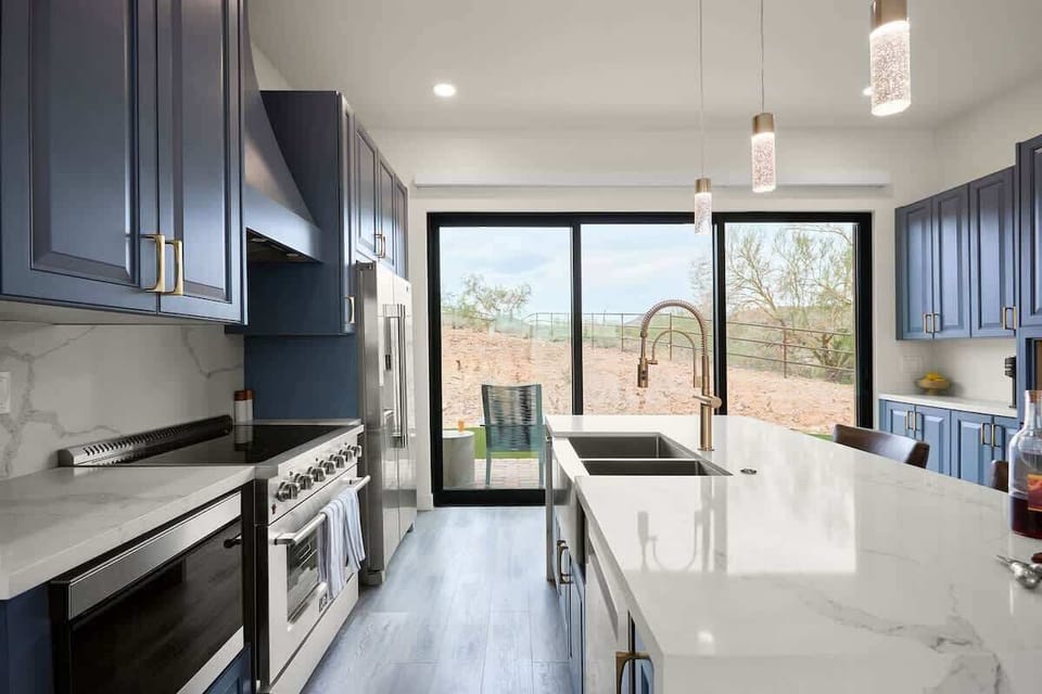 Fully equipped kitchen with stainless steel appliances, a sleek kitchen island with a breakfast bar for casual seating for 2.
