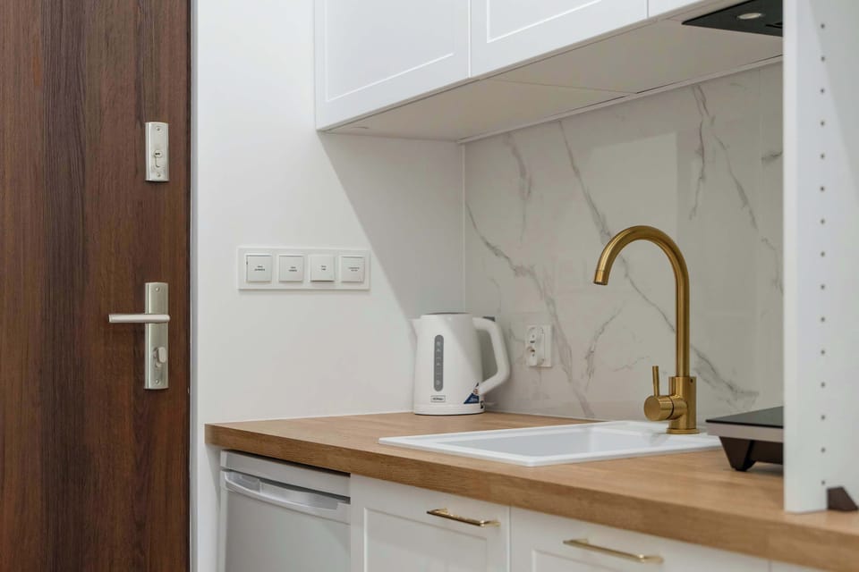 A corner of the kitchen with a kettle and storage shelves above. The mix of wood and white keeps the design fresh and clean.