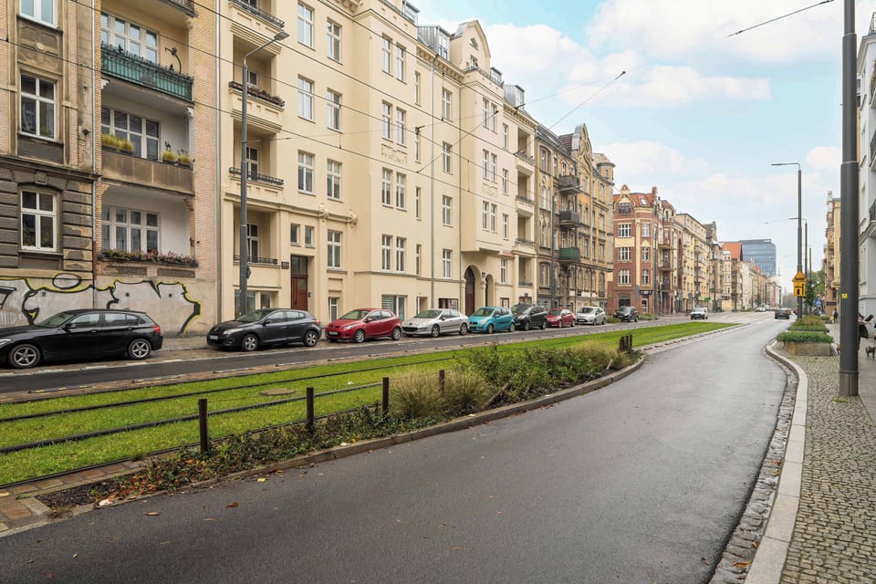 A broader view of the same street with a clear blue sky and wide sidewalks. The peaceful surroundings suggest a well-kept urban neighborhood.