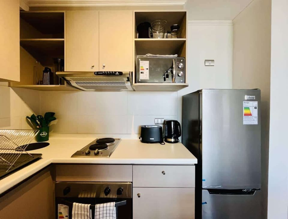 Compact kitchen w/ sleek cabinets & stainless steel fridge