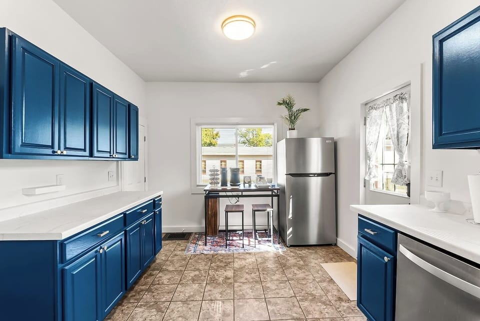 Cozy kitchen with bright blue cabinets and a sunny breakfast nook, perfect for family meals and morning coffee. Enjoy a space that combines modern style with homey charm.