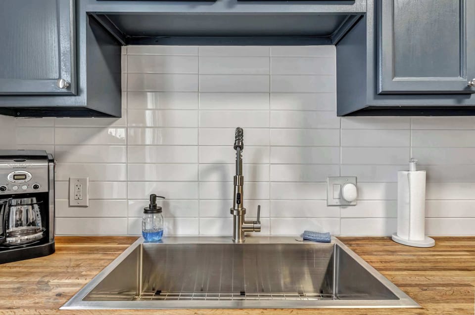 Sleek and spotless kitchen sink area featuring a deep stainless basin, modern faucet, and warm butcher-block counters — perfect for morning coffee prep or easy cleanups after home-cooked meals.