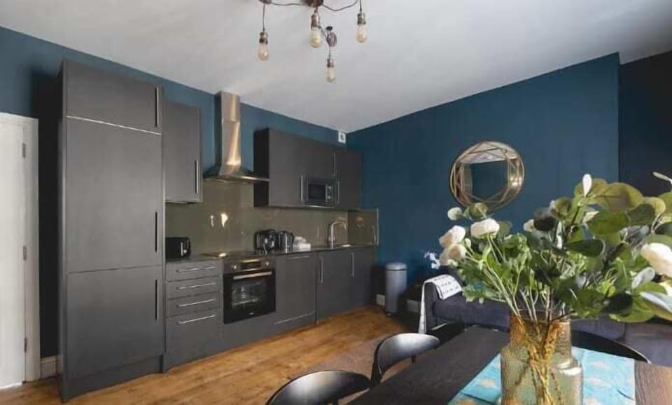 Modern black kitchen with teal walls and gold accents

