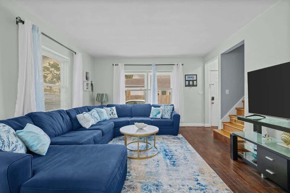 Bright and inviting living area with a cozy blue sectional sofa, perfect for relaxing or watching TV.