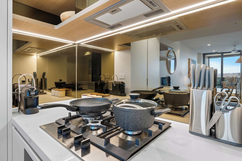 Modern kitchen with gas cooktop, premium cookware, and complimentary coffee capsules