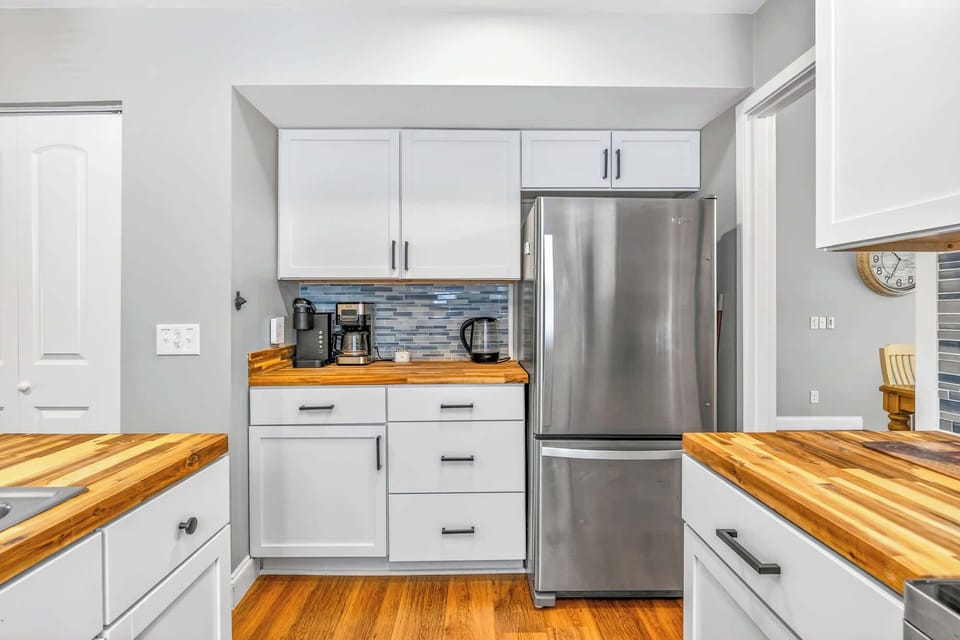 Gleaming stainless steel meets the rich grain of wood counters in this efficient coffee nook. Cool blue tiles add a splash of color to the bright, airy kitchen, making it a cheerful spot to brew your first cup of the day.