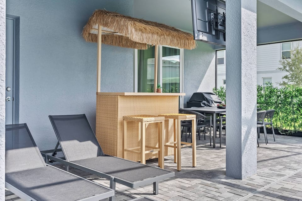 Soak up the sun on stylish lounge chairs next to a cozy tiki bar, where you can enjoy refreshing drinks. This inviting outdoor space is perfect for socializing or relaxing in the fresh air.