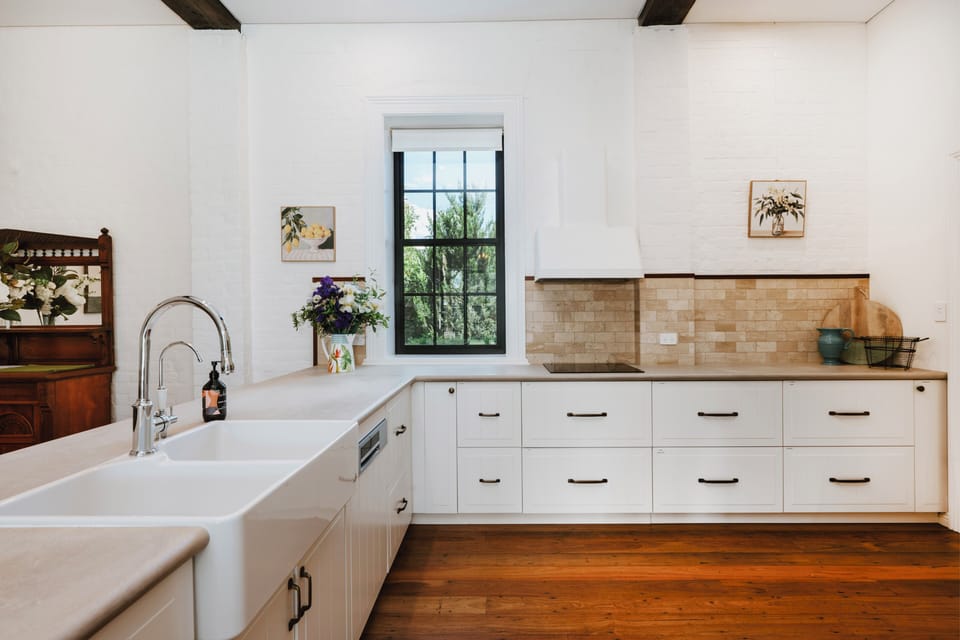 The chef’s kitchen blends heritage character with modern functionality, featuring Caesarstone benchtops, Bosch double ovens, an induction cooktop, an integrated fridge and freezer, and a walk-in pantry.