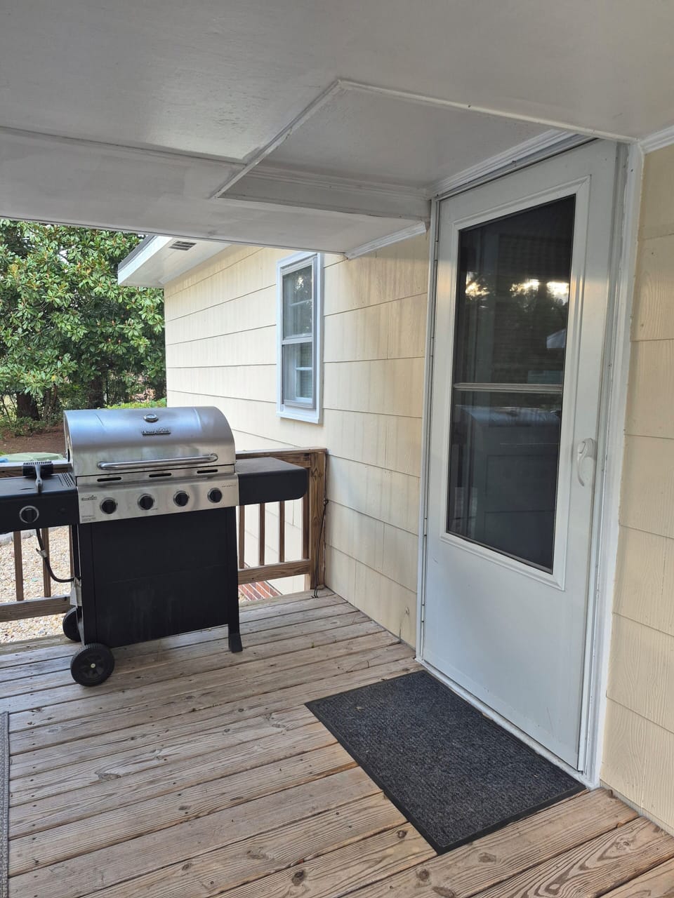 Covered back porch with propane grill, sectional couch, and table.