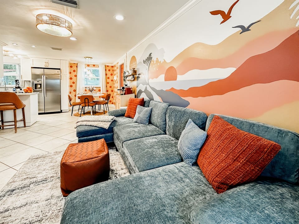 Living Room with Couch, 65" Roku TV, Indoor Electric LED Fire Place, Fandelier & Local Artist Mural