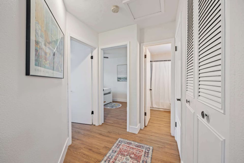 Hallway with wood flooring leading to bedrooms and a bathroom with a shower curtain.