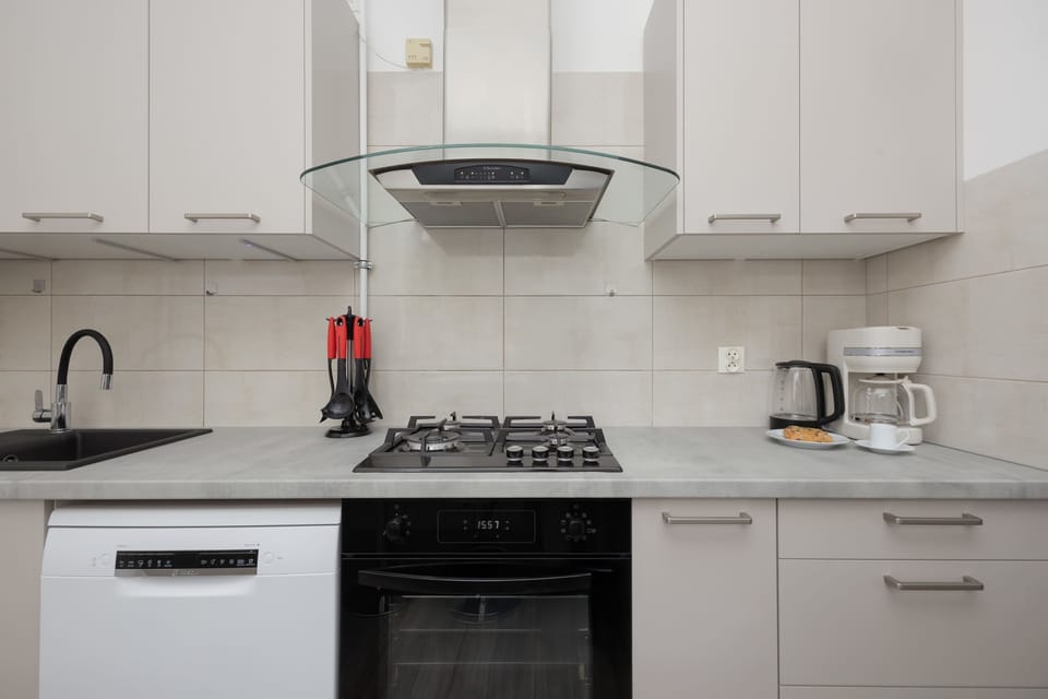 Another kitchen angle showing the countertop, stove, and upper cabinets. The bright tiles and neat arrangement create a tidy appearance.