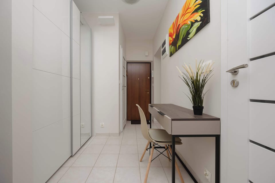 A hallway with light wood floors and a decorative plant at the end. Simple and elegant design details enhance the clean lines.
