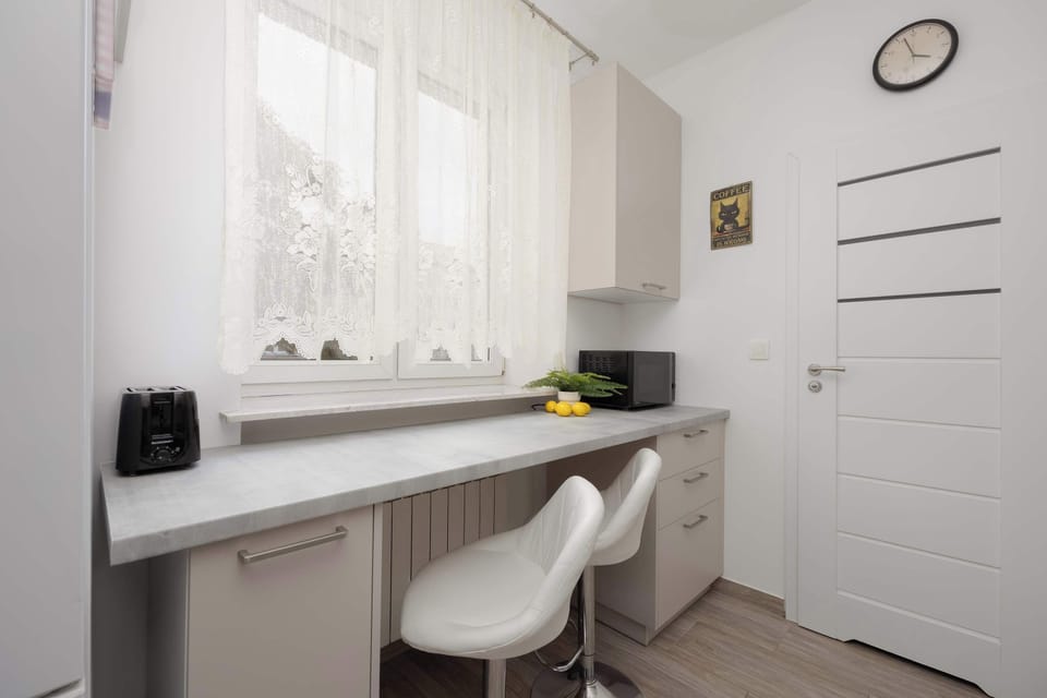 A small work area with a desk, chair, and window letting in natural light. The neutral tones make it feel comfortable and practical for working.