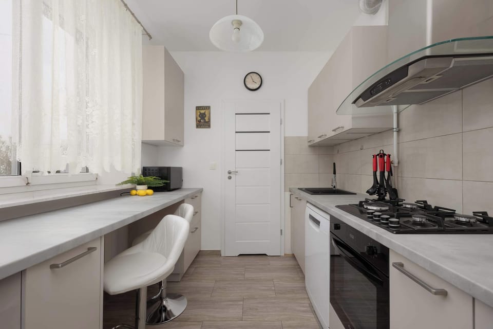 Another kitchen angle showing the countertop, stove, and upper cabinets. The bright tiles and neat arrangement create a tidy appearance.