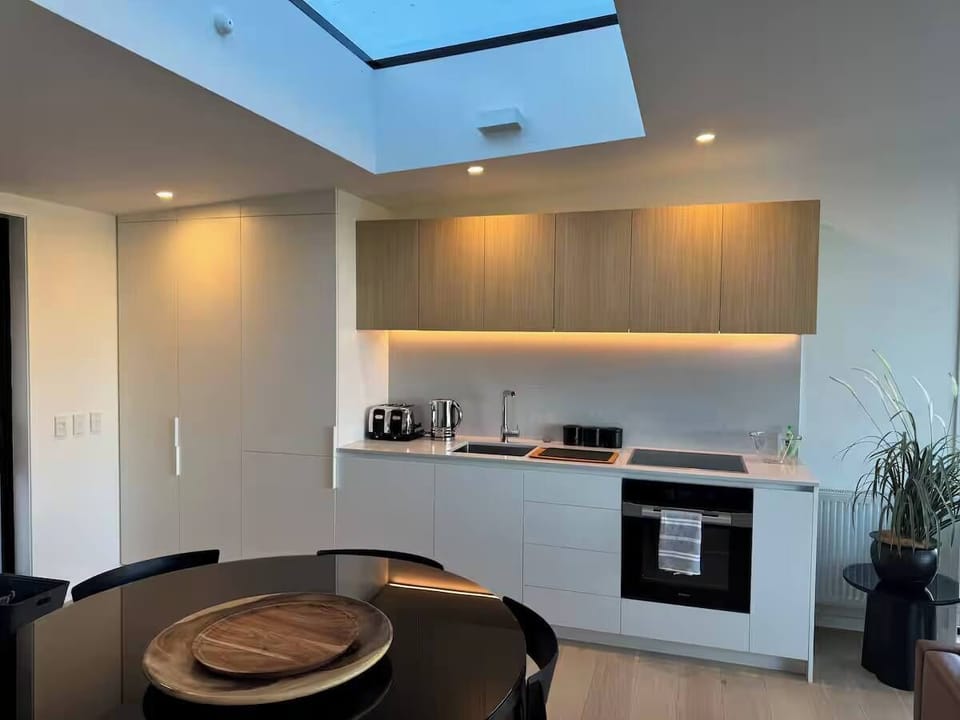 Open plan kitchen, living and dining space with ambient lighting and a sky light