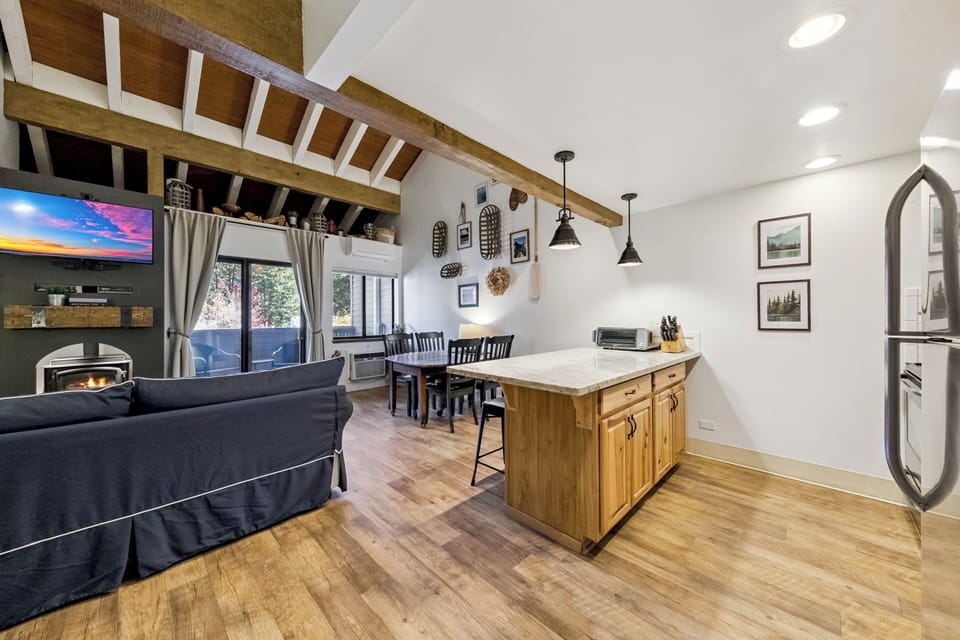 Unwind in your cozy open-concept living space where rustic beams meet modern comfort, perfect for cooking and relaxing together.
