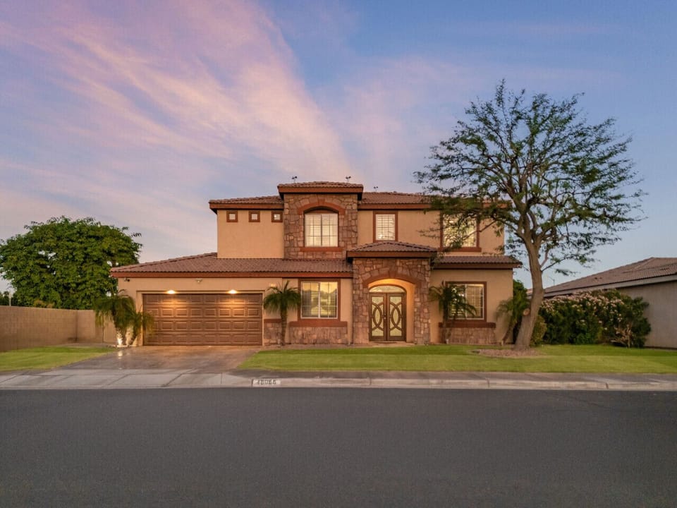 Grand front exterior w/ desert landscaping, warm tones & a welcoming entry that sets the tone on arrival.