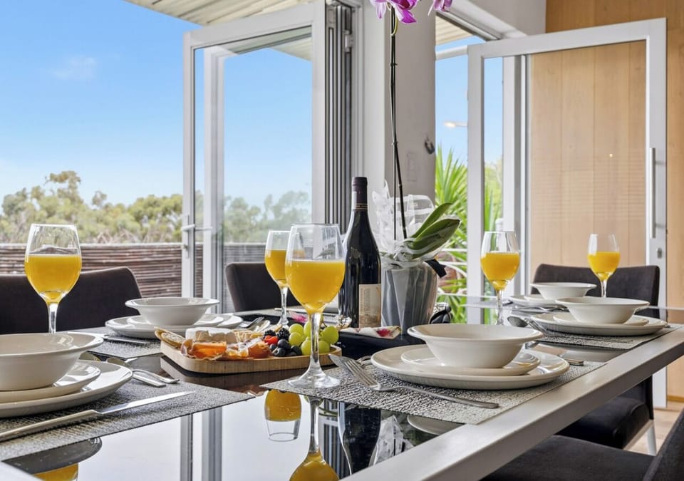 Wine-ready dining table with open glass doors and refreshing outdoor views