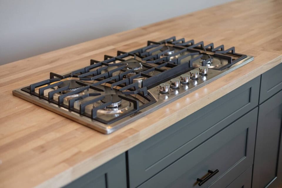 Five-burner gas cooktop built into a butcher block island for easy meals.