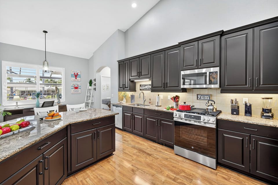 Modern kitchen featuring a large breakfast bar with seating for six, stainless steel appliances, and plenty of counter space for cooking and entertaining.