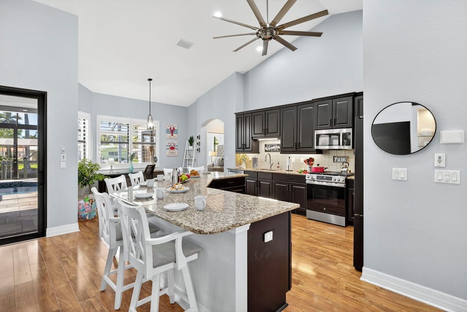 Open-concept living, dining, and kitchen area with a large breakfast bar that seats six, stainless steel appliances, and stylish finishes creating a bright, inviting space for gathering and entertaining.