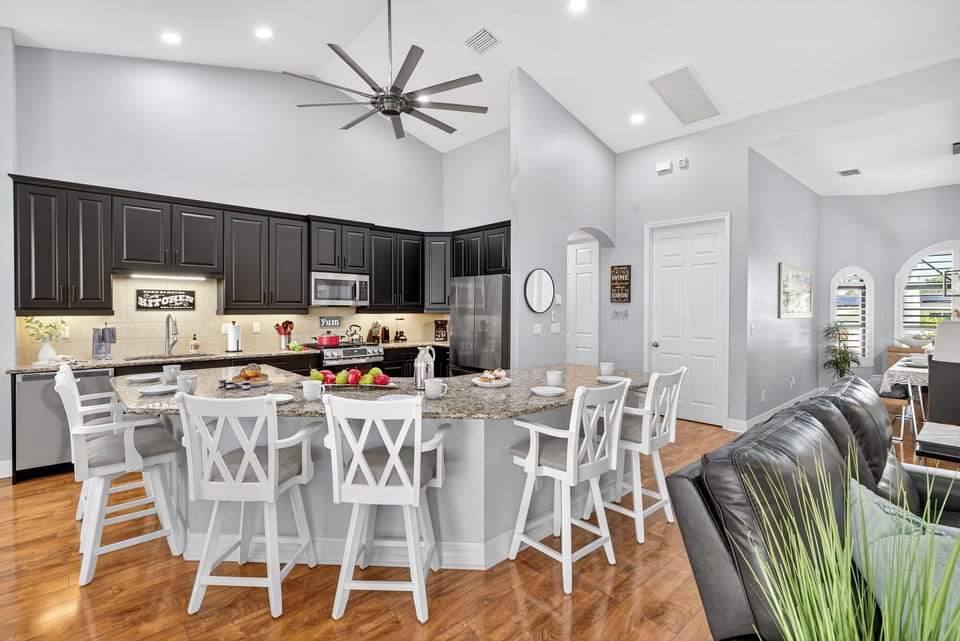Open-concept living, dining, and kitchen area with a large breakfast bar that seats six, stainless steel appliances, and stylish finishes creating a bright, inviting space for gathering and entertaining.