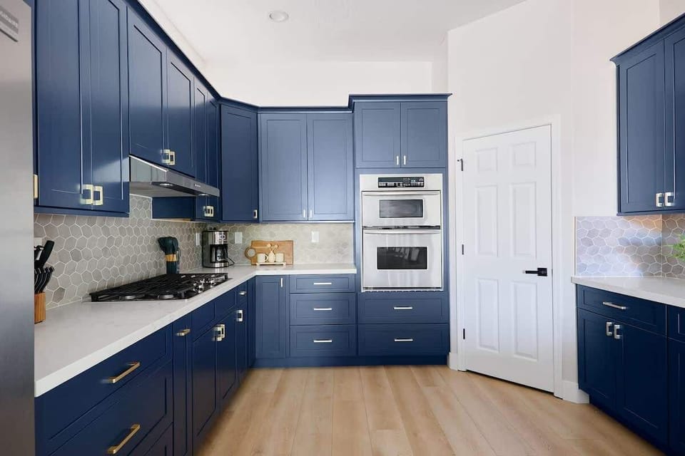 Stylish and functional kitchen with stainless steel appliances, navy cabinetry, marble countertops, and a spacious island with breakfast bar seating for 4.