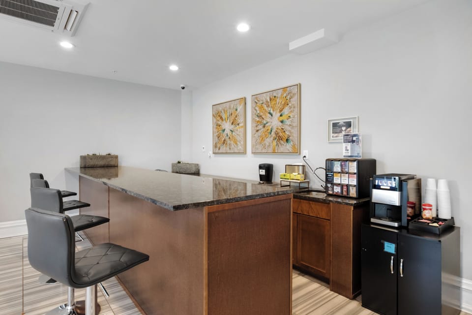 Lounge coffee station with breakfast bar, espresso machine, and modern cabinetry providing convenient shared gathering space.