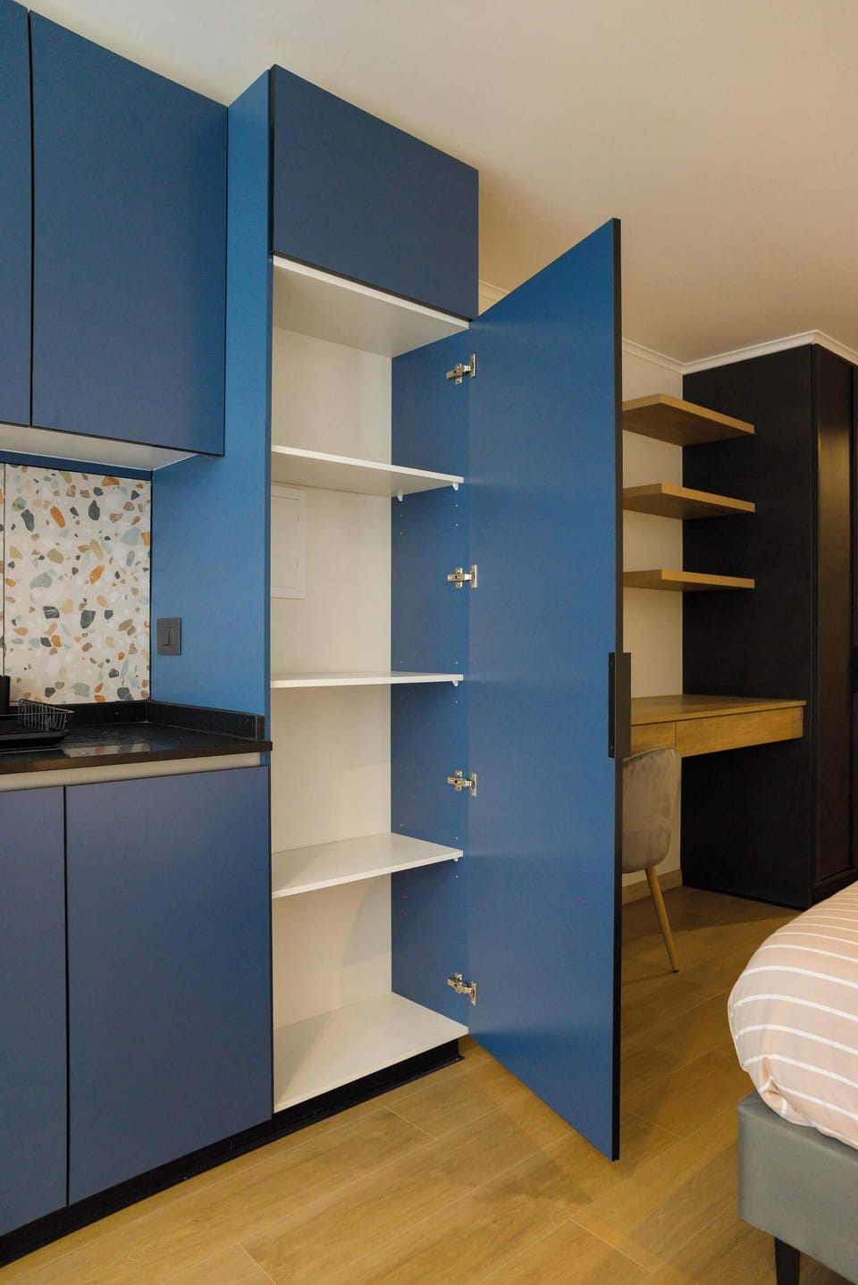 Explore this modern studio kitchen with ample storage and stylish blue cabinets, perfect for a cozy stay.
