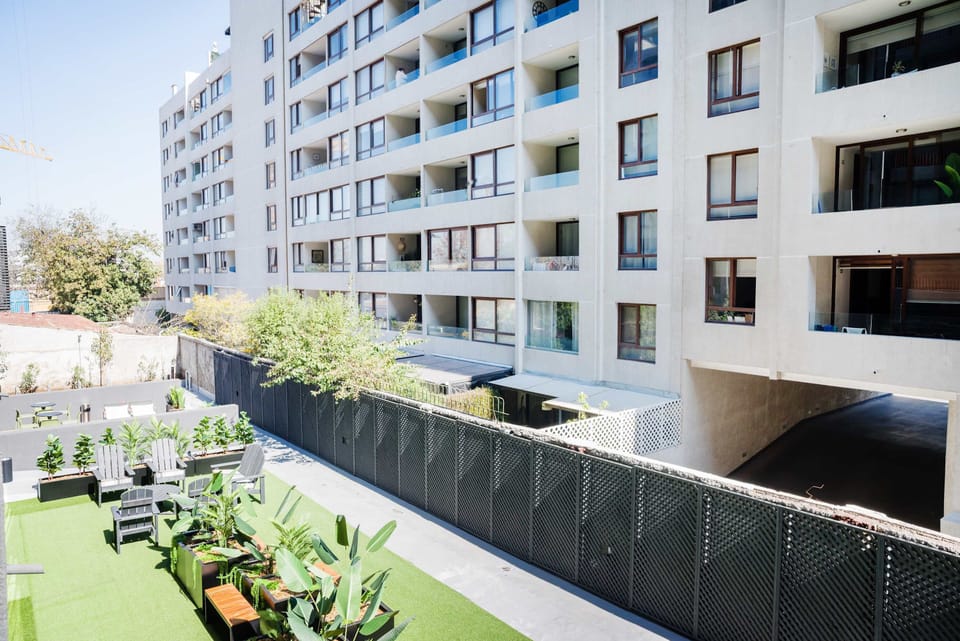 Enjoy the vibrant shared outdoor space with lush greenery and comfortable seating, ideal for sunny gatherings. (Common Area)