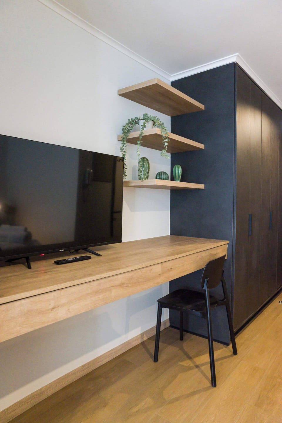 Sleek workspace with TV and stylish shelving, perfect for work or relaxation in a cozy studio.