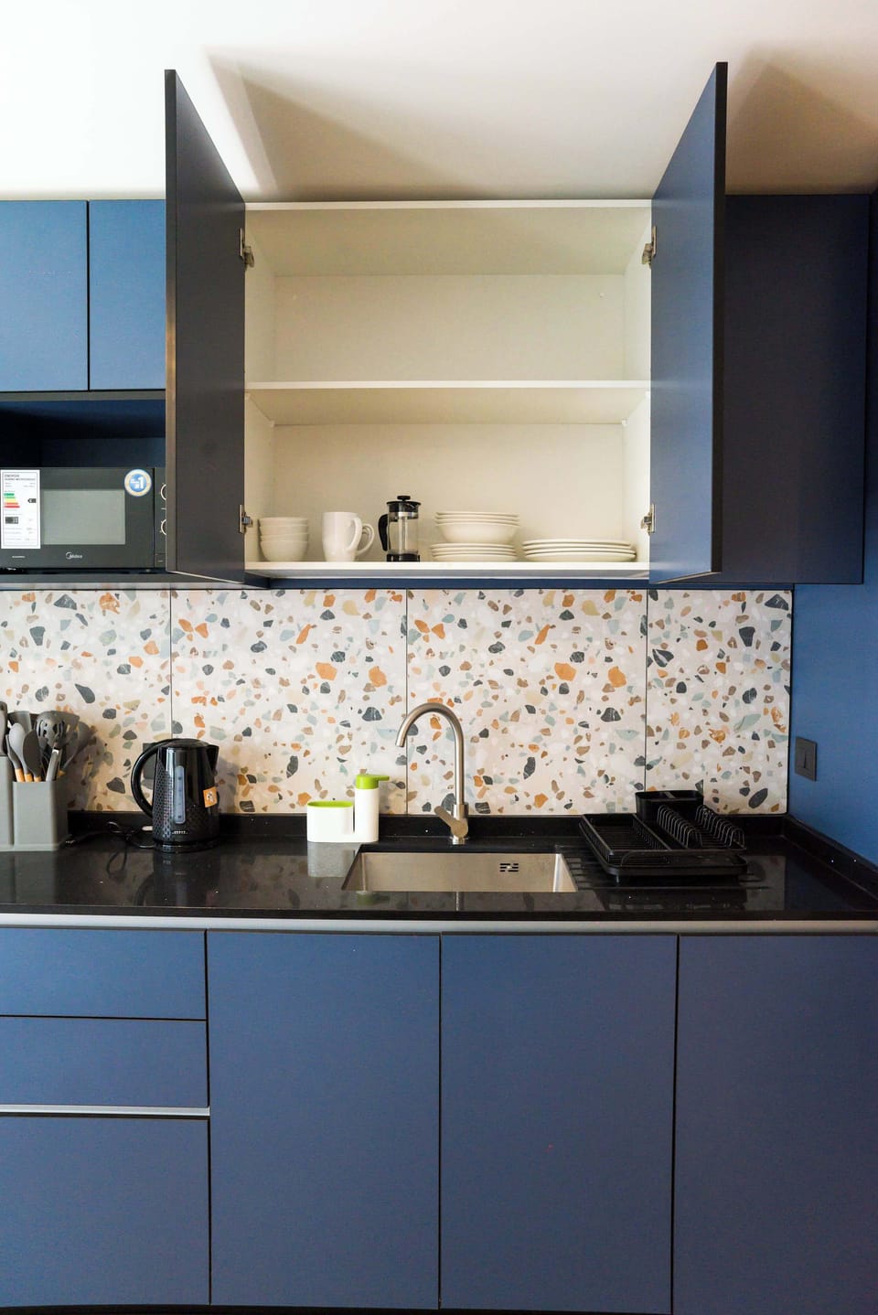 Stylish kitchen with terrazzo backsplash and sleek blue cabinets, ideal for culinary adventures in a cozy studio.
