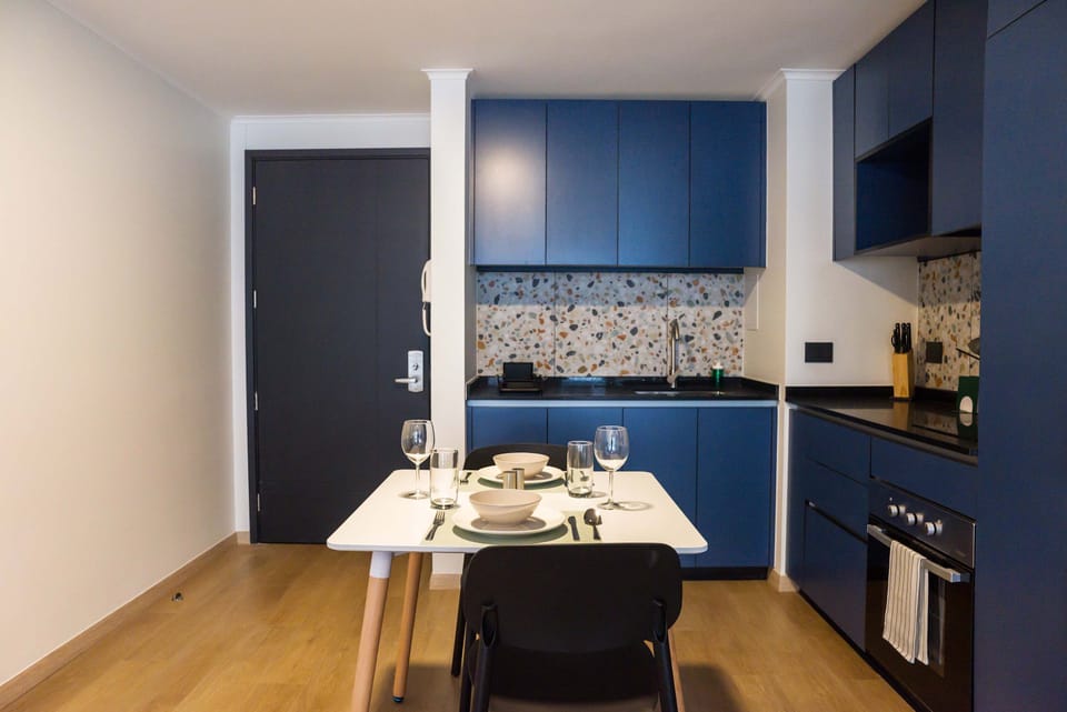Chic kitchen with blue cabinetry and terrazzo backsplash, ideal for cozy meals in a stylish studio.