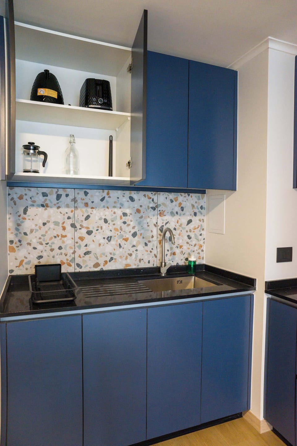 Sleek kitchen with terrazzo backsplash and modern blue cabinets, ideal for culinary adventures.