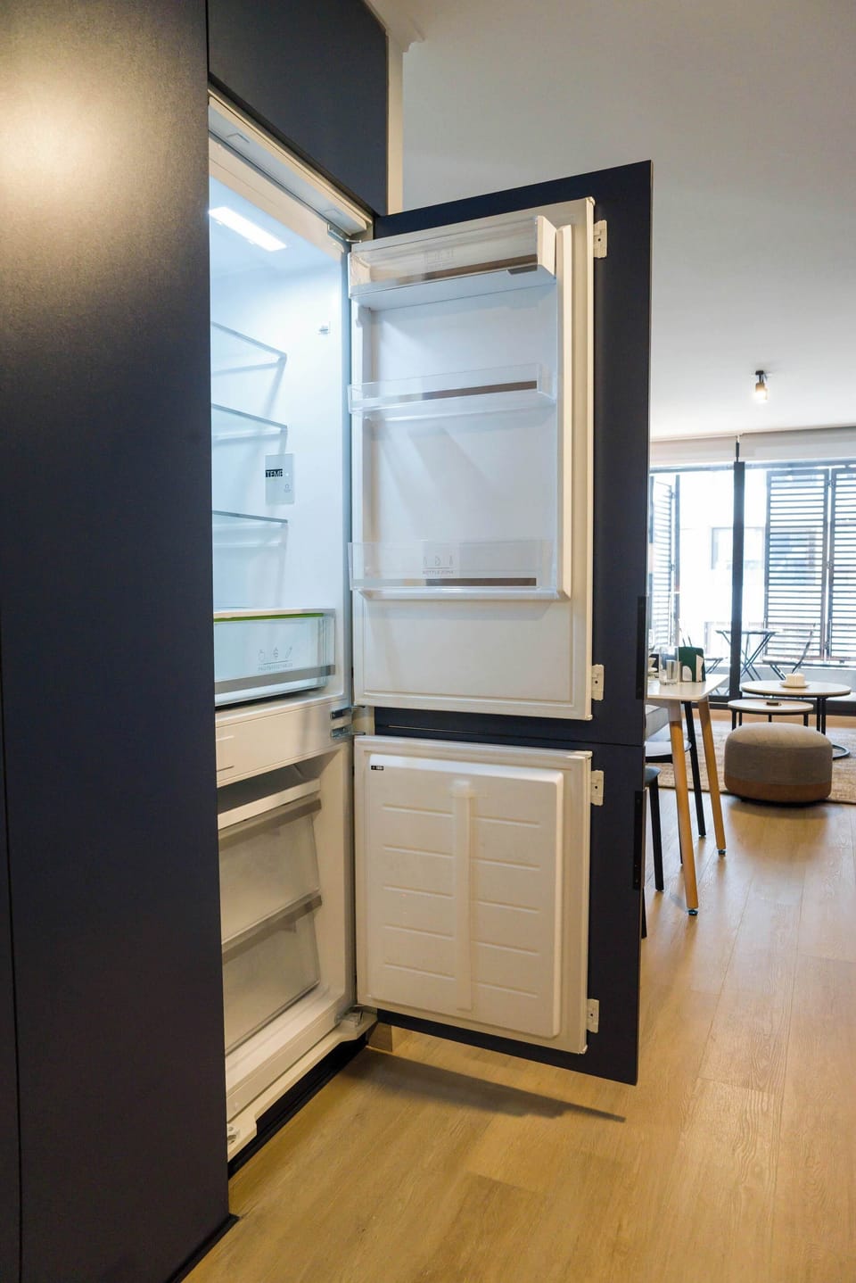 Sleek kitchen with modern blue cabinetry and open layout, seamlessly connecting to dining and living areas.
