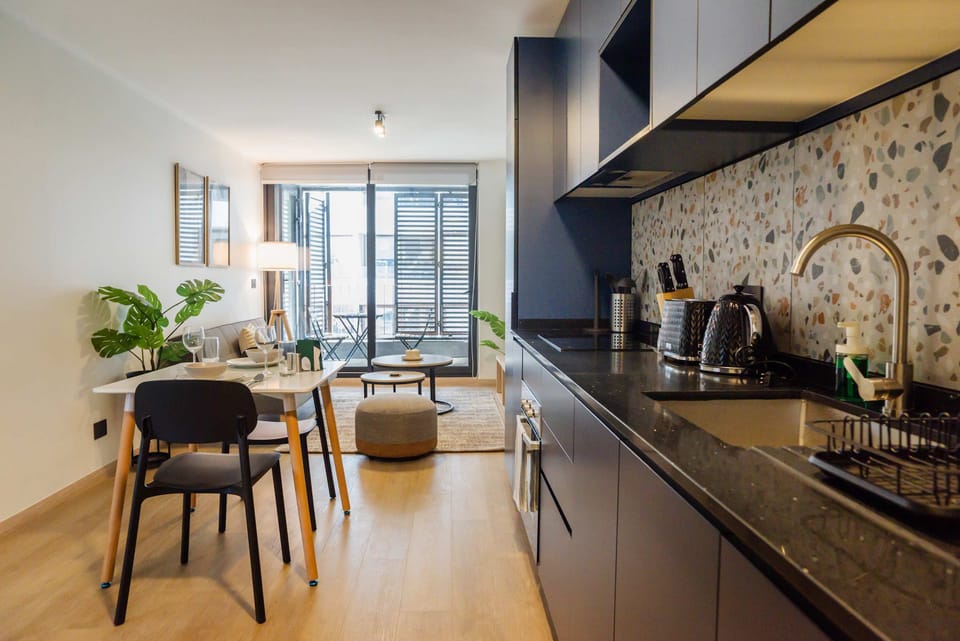 Modern kitchen and living area with sleek design, natural light, and a cozy balcony for relaxation.