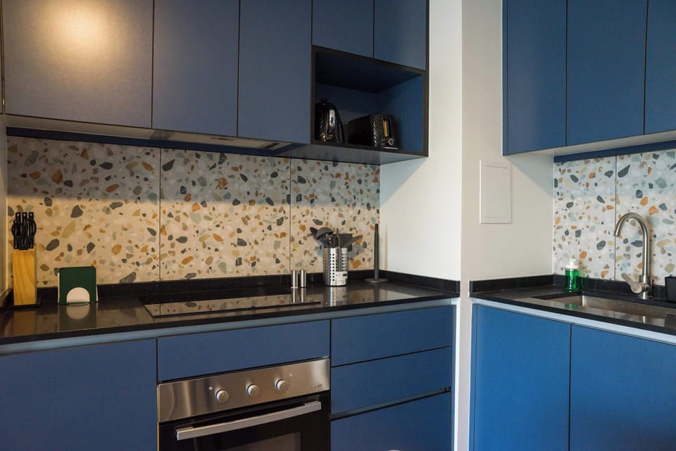 Stylish kitchen with blue cabinets and terrazzo backsplash, ideal for culinary creativity.