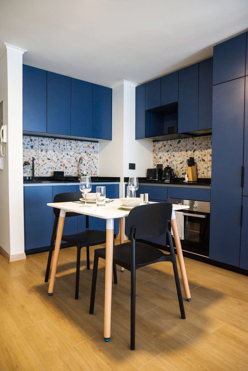 Sleek kitchen with blue cabinets and terrazzo backsplash, ideal for cozy meals in a stylish setting.